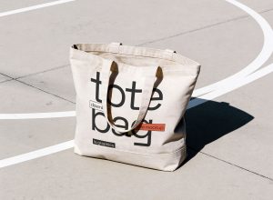 Free canvas tote bag mockup PSD in a sunlit outdoor setting for branding and merchandise presentation in Photoshop